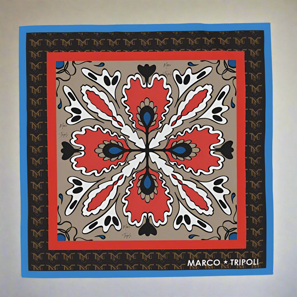 Decorative scarf with a geometric pattern featuring red, black, and white colors on a beige background. Brand 'Marco Tripoli' is visible.